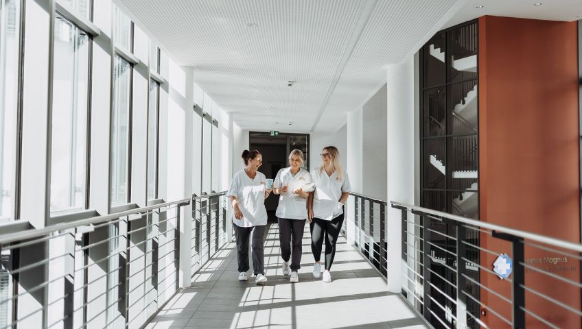 Drei lachende Mitarbeiterinnen in einem Gang des Albertus Magnus Zentrums in Siegen.