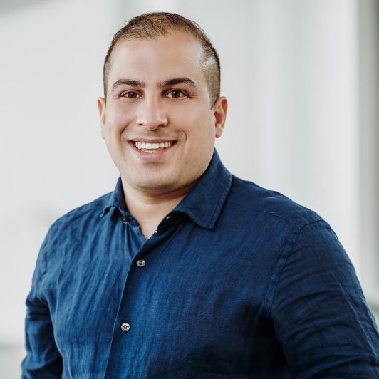 Portraitfoto von Dr. med. Arya B. Khorsandi, Facharzt für Neurologie. Er trägt ein dunkelblaues Hemd und lächelt in die Kamera.
