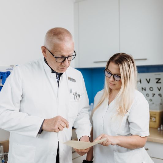 Dr. med. Rainer Lindemuth von NEURO Südwestfalen im weißen Kittel im Gespräch mit einer medizinischen Fachangestellten