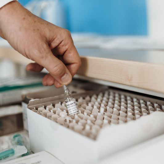 Eine Hand greift aus einer Box eine Ampulle Procain als Teil der Neuraltherapie