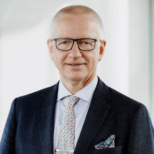 Portraitfoto von Dr. med. Rainer Lindemuth, Facharzt für Neurologie. Er trägt einen schwarzen Anzug, ein hellgraues Hemd und eine bunt gemusterte Krawatte. Er lächelt in die Kamera.
