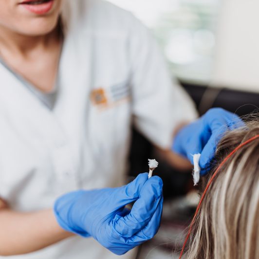 IgeL-Leistungenin Burbach Nahaufnahme einer medizinischen Fachangestellten, die einer Patientin Sonden am Kopf anbringt.